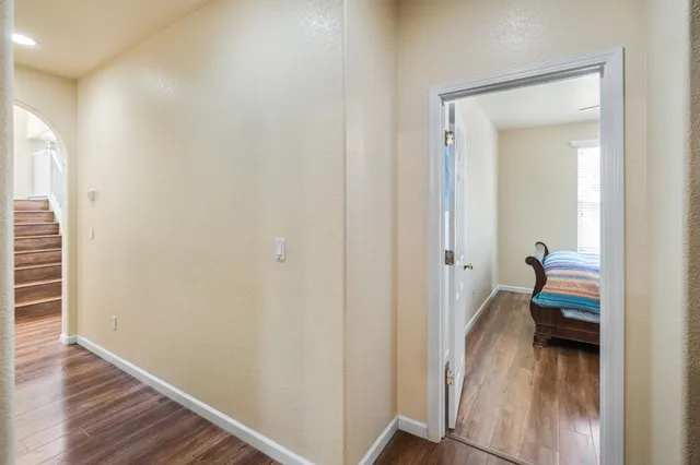 a view of a hallway with a livingroom and a bedroom with wooden floor