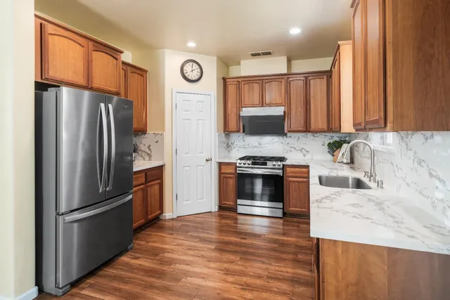 a kitchen with granite countertop a refrigerator and a stove top oven