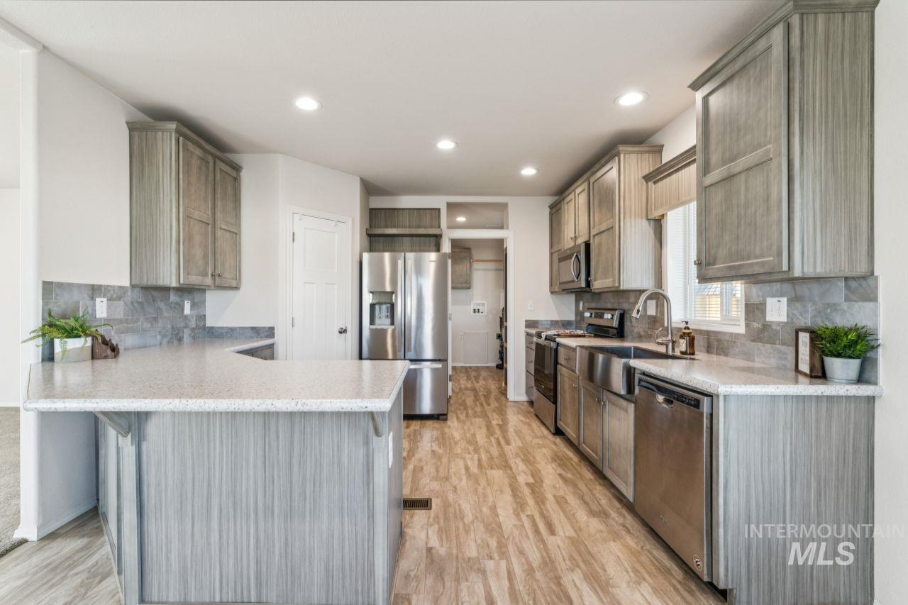 2750 Alden Road, Unit 2 Fruitland, ID 83619 - Photo 3 of 24 Kitchen featuring backsplash, a peninsula, appliances with stainless steel finishes, a breakfast bar, and light wood-type flooring