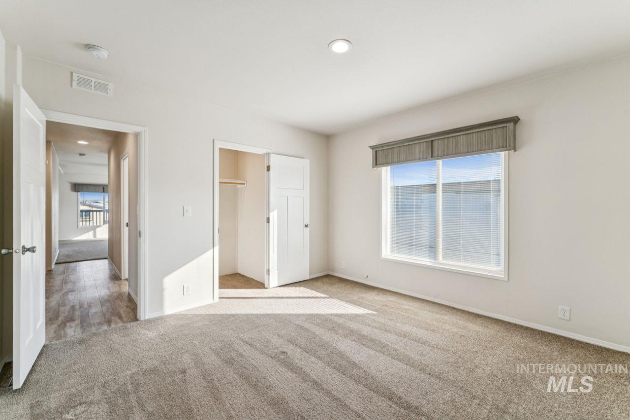 2750 Alden Road, Unit 2 Fruitland, ID 83619 - Photo 8 of 24 Unfurnished bedroom with carpet flooring, a spacious closet, multiple windows, and recessed lighting
