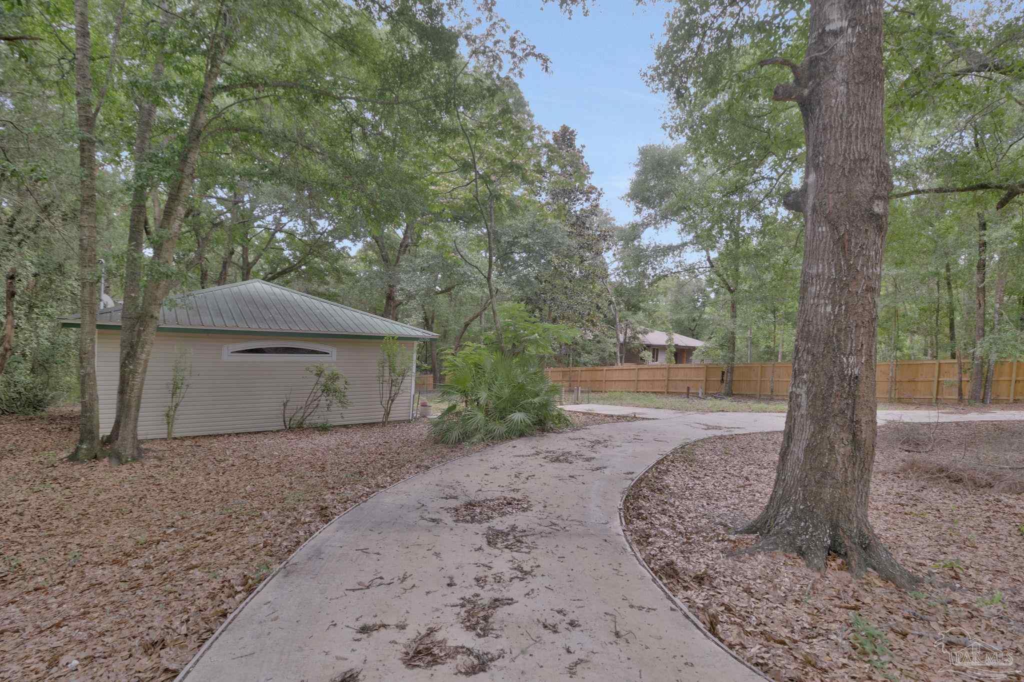 10290 West Lake Road Milton, FL 32583 - Photo 40 of 53 a backyard of a house with large trees and a wooden fence
