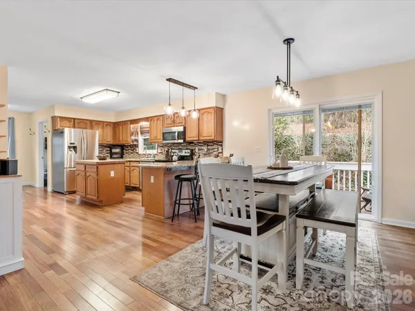 a kitchen with stainless steel appliances a stove a refrigerator white cabinets and chairs