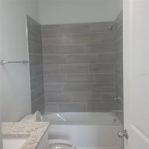 a bathroom with a granite countertop bathtub shower and toilet