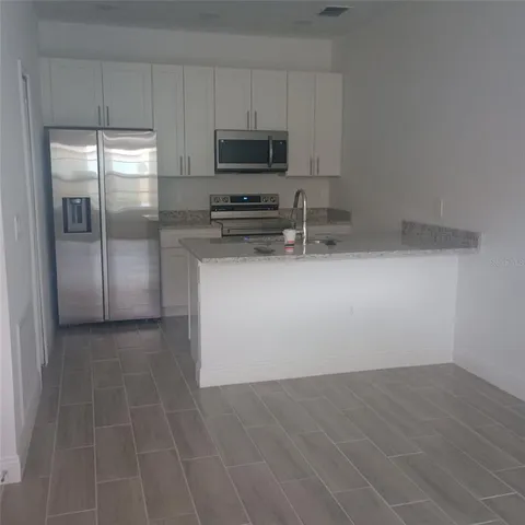 a kitchen with granite countertop a refrigerator and a stove top oven