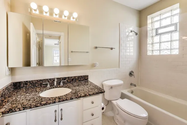a bathroom with a granite countertop sink a toilet and shower