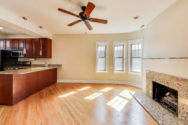 a kitchen with stainless steel appliances granite countertop a stove top oven a sink dishwasher a refrigerator and a fireplace with wooden floor