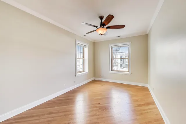 a view of empty room with wooden floor and fan