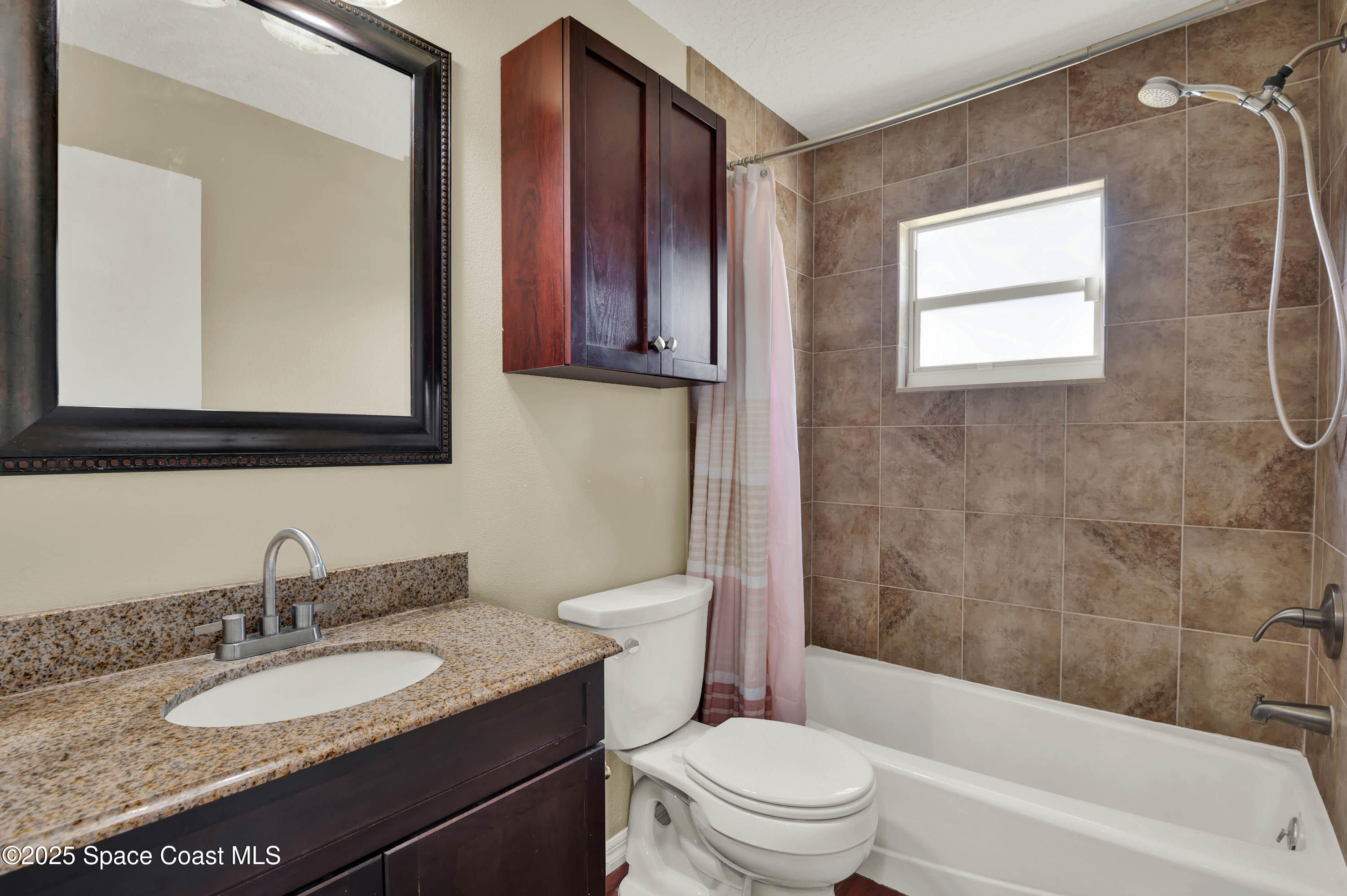 930 Miller Lane Melbourne, FL 32934 - Photo 22 of 40 a bathroom with a granite countertop toilet a sink and a mirror