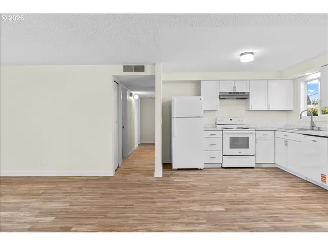 a kitchen with wooden floors and white appliances
