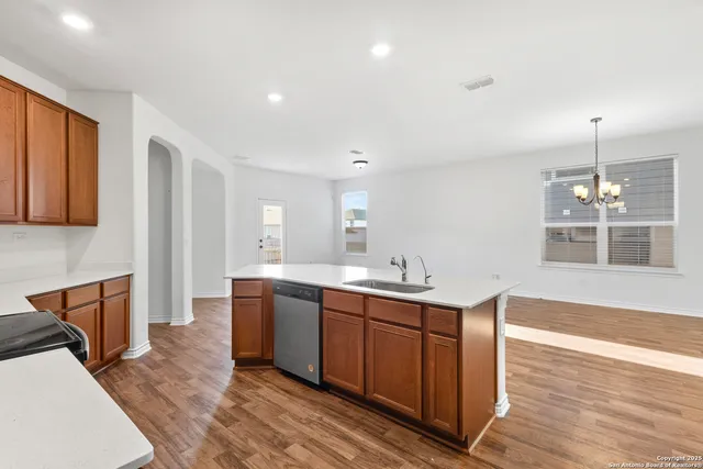 a view of a kitchen with stainless steel appliances granite countertop a sink and dishwasher a stove with wooden floor