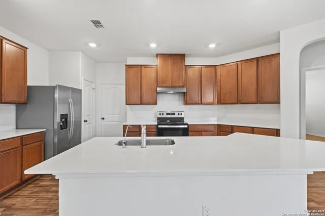 a kitchen with stainless steel appliances kitchen island a sink a stove a refrigerator and cabinets
