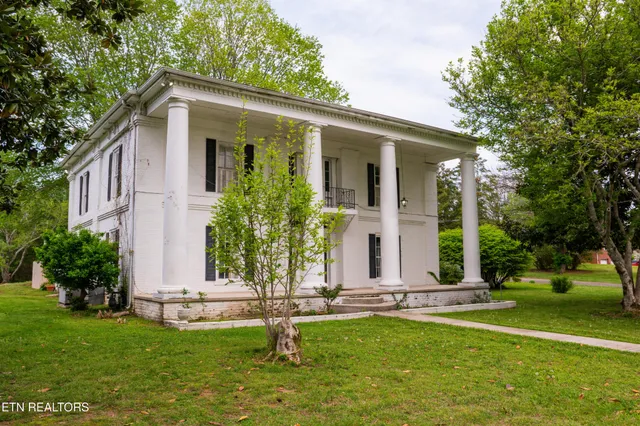 a front view of a house with a garden and trees