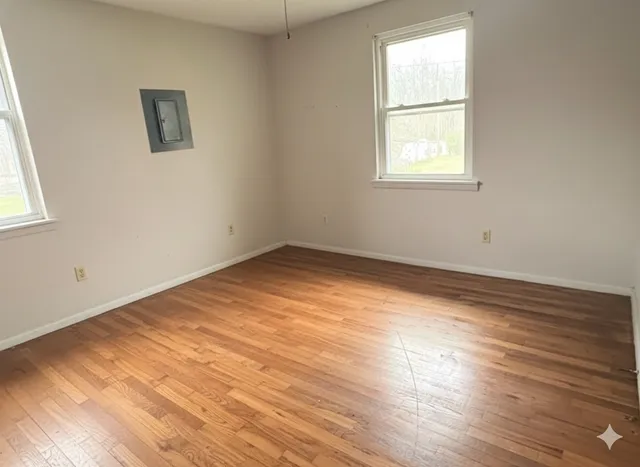an empty room with wooden floor and windows