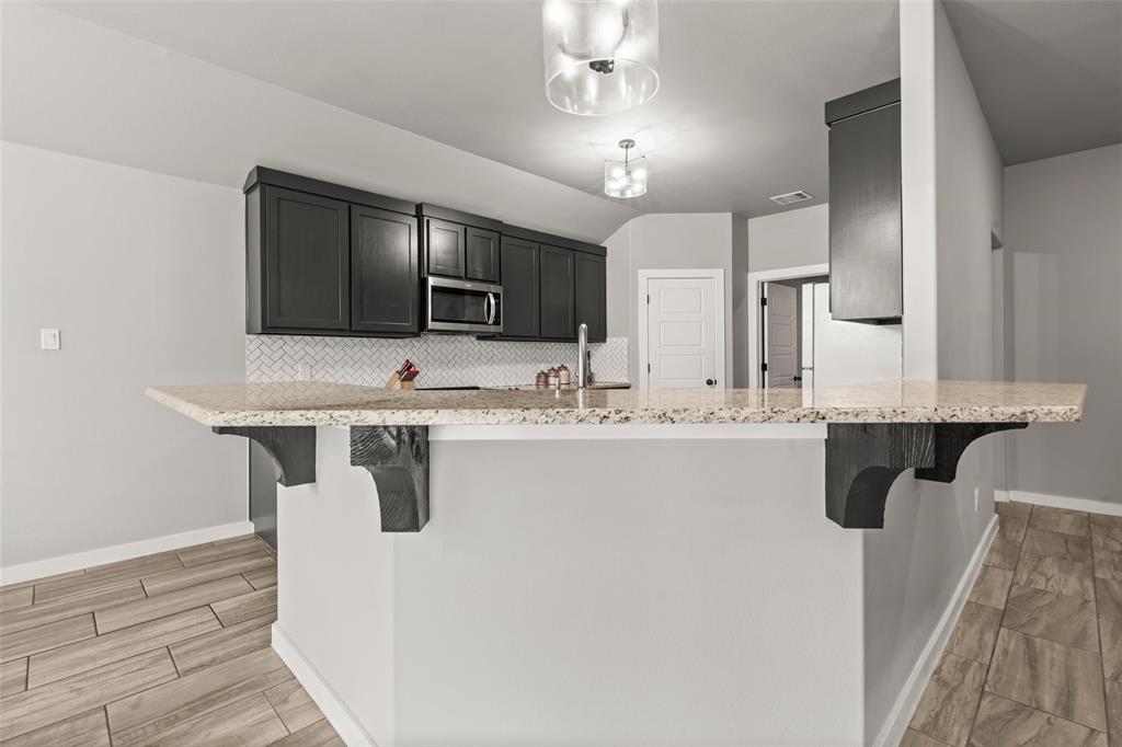 1034 Antelope Trail Temple, TX 76504 - Photo 6 of 24 a kitchen with kitchen island granite countertop a sink and a refrigerator