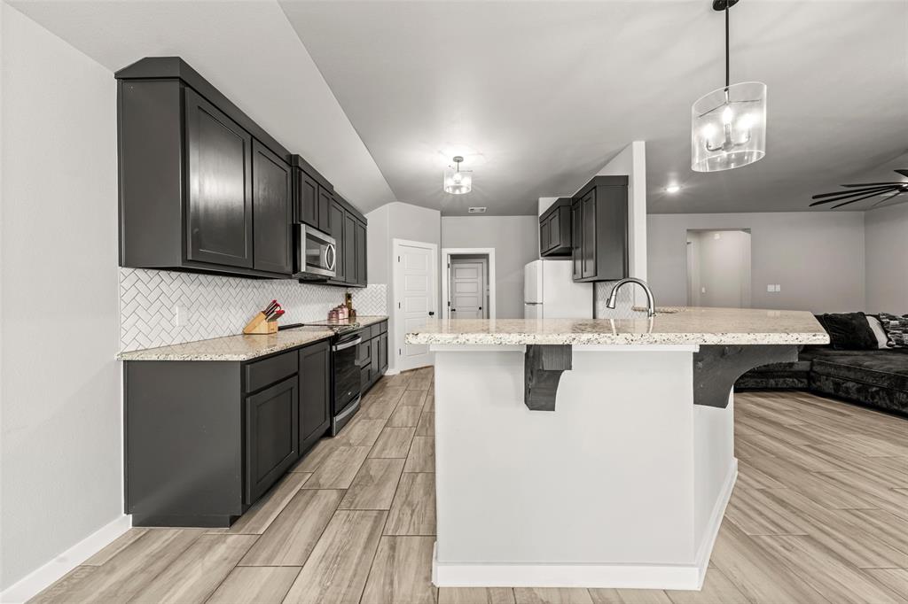 1034 Antelope Trail Temple, TX 76504 - Photo 23 of 24 a large kitchen with stainless steel appliances kitchen island granite countertop a stove a sink dishwasher and a refrigerator with wooden floor