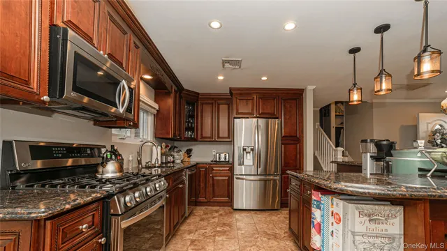 a kitchen with stainless steel appliances granite countertop a stove refrigerator sink and microwave