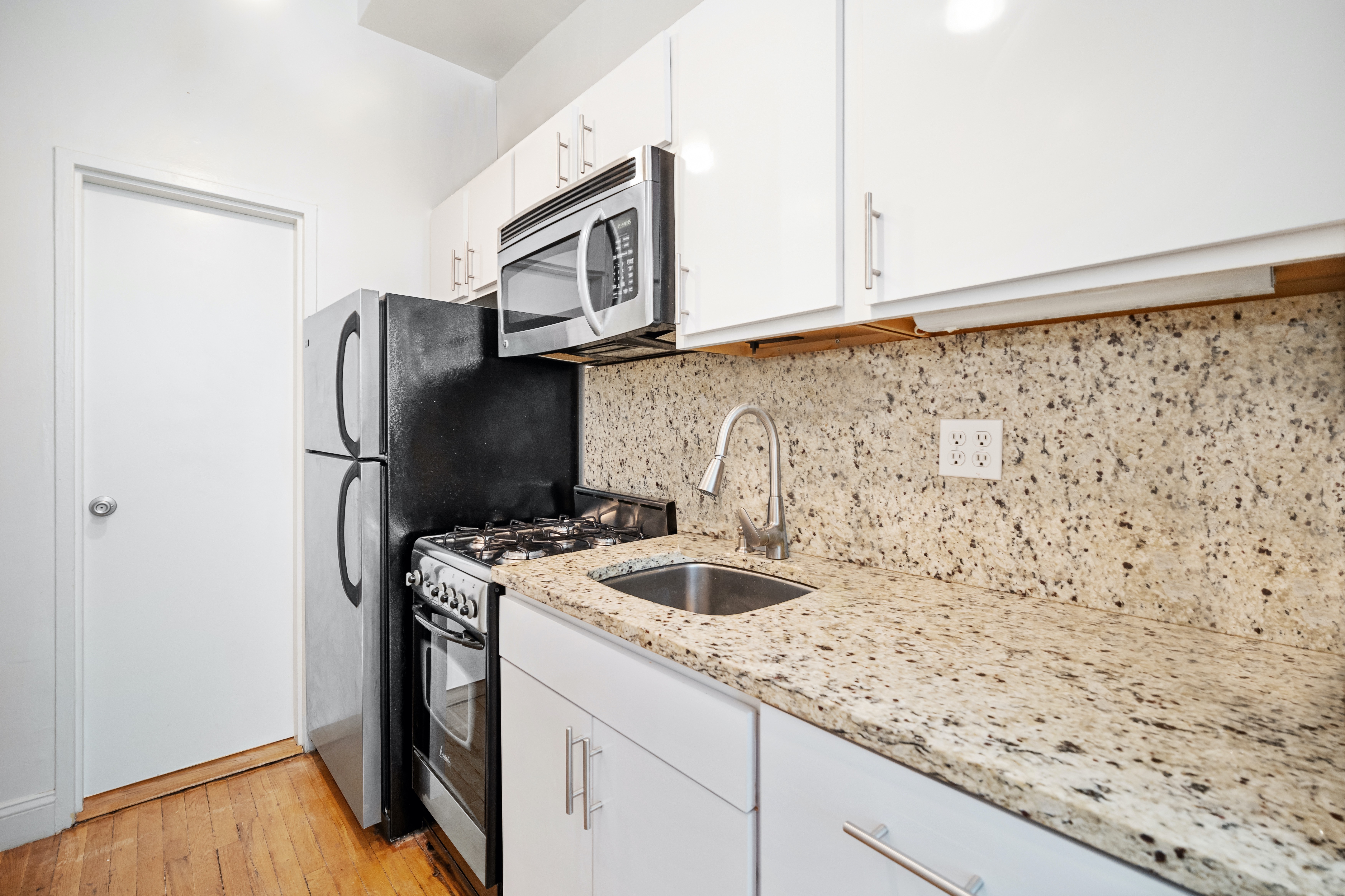 430 East 87th Street, Unit 1B Manhattan, NY 10128 - Photo 5 of 6 a kitchen with a sink and a refrigerator