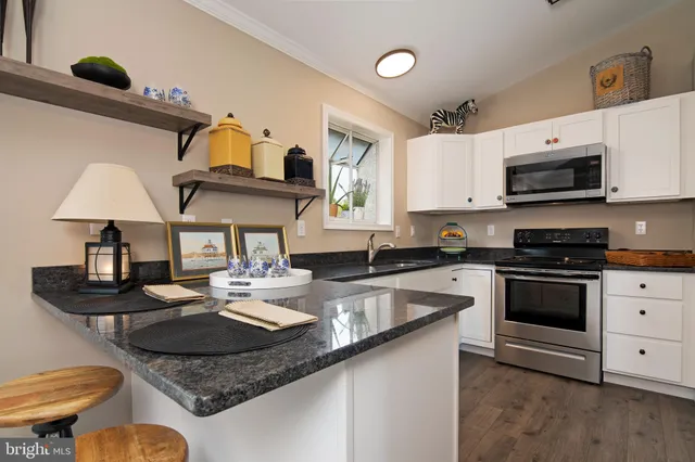a kitchen with granite countertop white cabinets stainless steel appliances and a sink