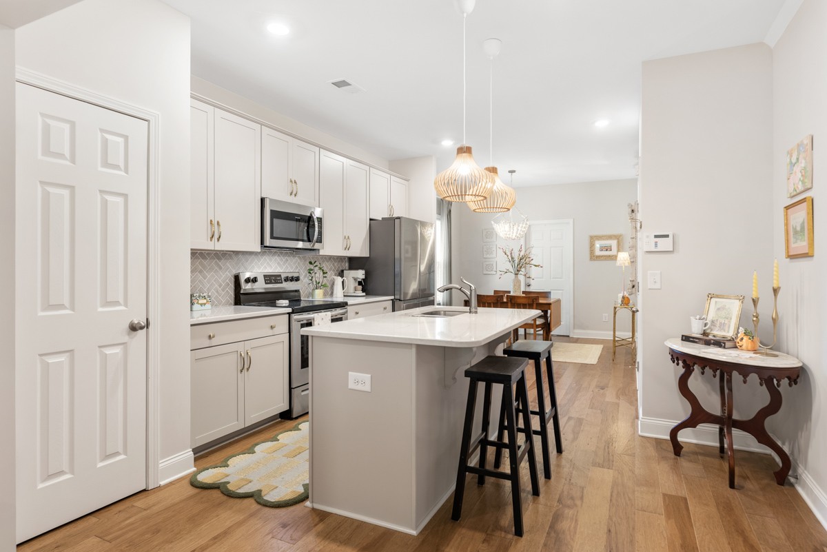 235 Grandstand Boulevard Gallatin, TN 37066 - Photo 7 of 26 a kitchen with kitchen island granite countertop wooden floors and white appliances