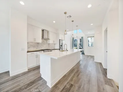 a large room with kitchen island a wooden floor and white cabinets