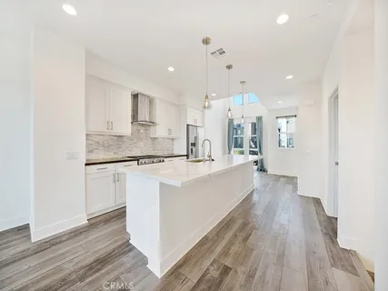 a large room with kitchen island a wooden floor and white cabinets