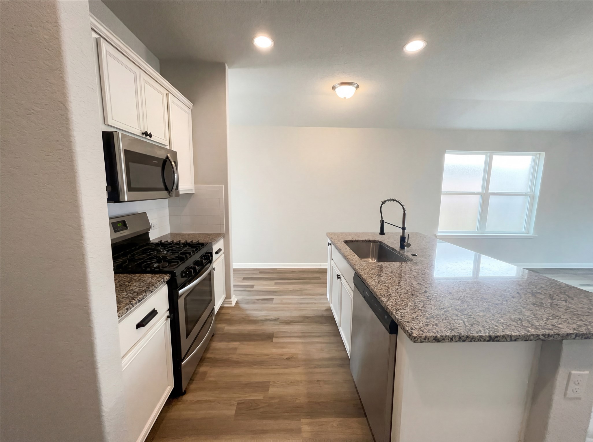 413 Dubina Avenue Georgetown, TX 78626 - Photo 17 of 22 Kitchen with stainless steel appliances, light wood-style floors, white cabinets, dark stone counters, and recessed lighting