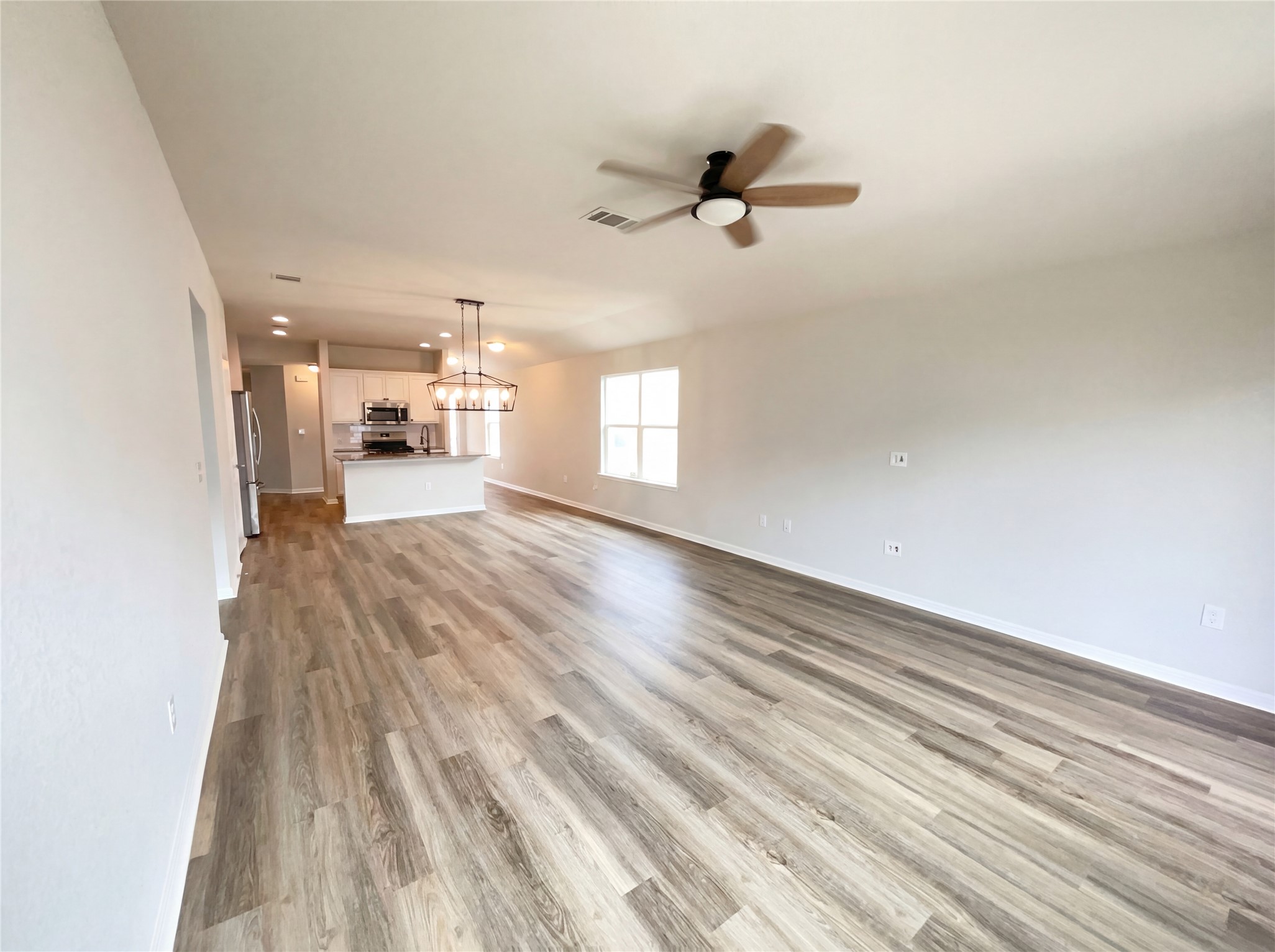 413 Dubina Avenue Georgetown, TX 78626 - Photo 3 of 22 Unfurnished living room featuring light wood-type flooring, a chandelier, and ceiling fan
