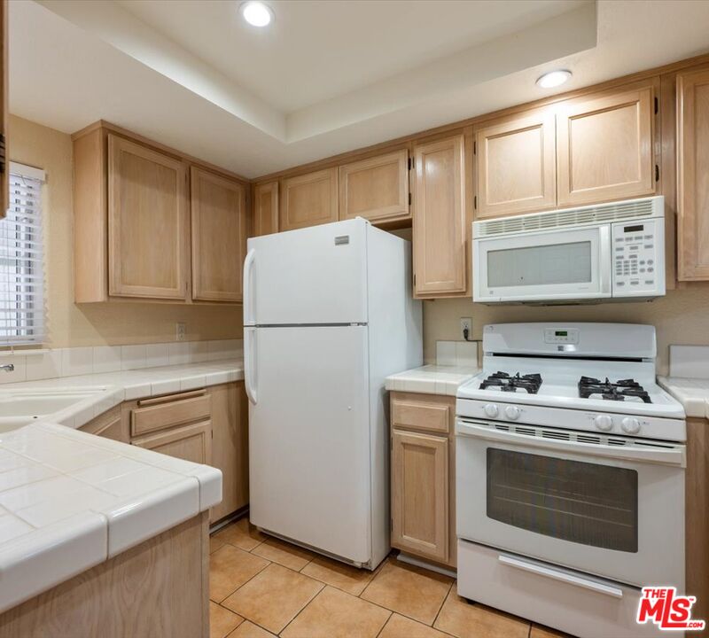 15114 Sherman Way, Unit 104 Van Nuys, CA 91405 - Photo 6 of 19 a kitchen with a stove a refrigerator and a sink