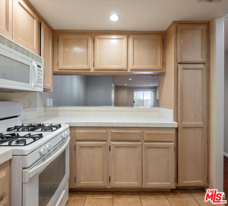 15114 Sherman Way, Unit 104 Van Nuys, CA 91405 - Photo 9 of 19 a kitchen with white cabinets and appliances