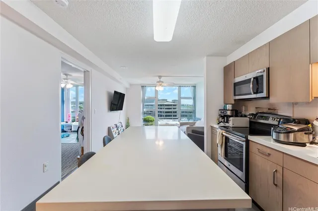 a large kitchen with kitchen island a large counter top space a sink a window and stainless steel appliances