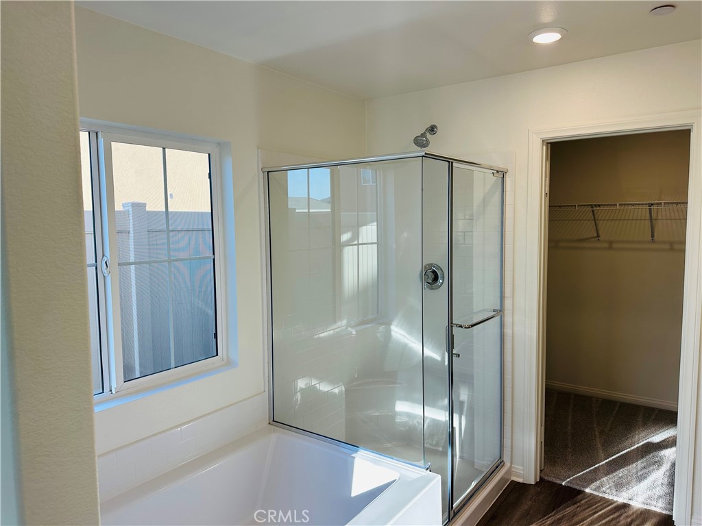 916 Runaway Trail San Jacinto, CA 92582 - Photo 18 of 23 a bathroom with a glass shower door and a mirror