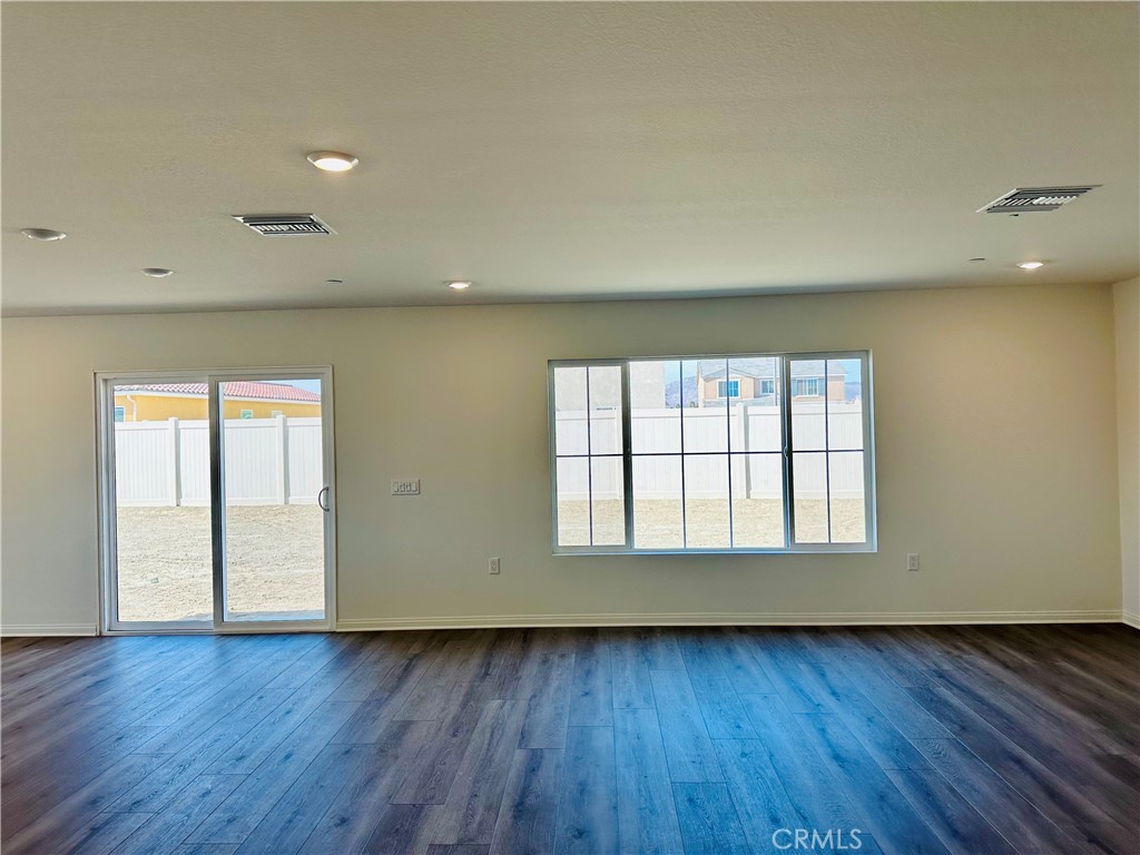 916 Runaway Trail San Jacinto, CA 92582 - Photo 7 of 23 an empty room with wooden floor and windows