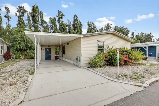 a view of a white house with a small yard and potted plants
