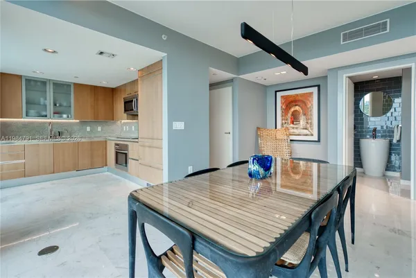 a kitchen with stainless steel appliances granite countertop a kitchen island a stove a dining table and chairs