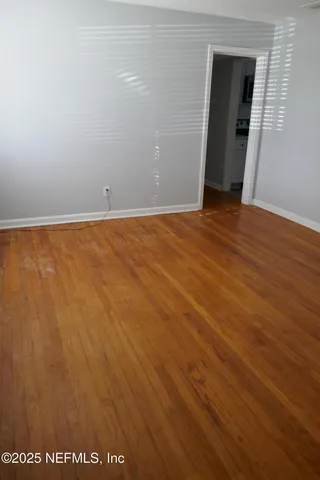 an empty room with wooden floor and mirror