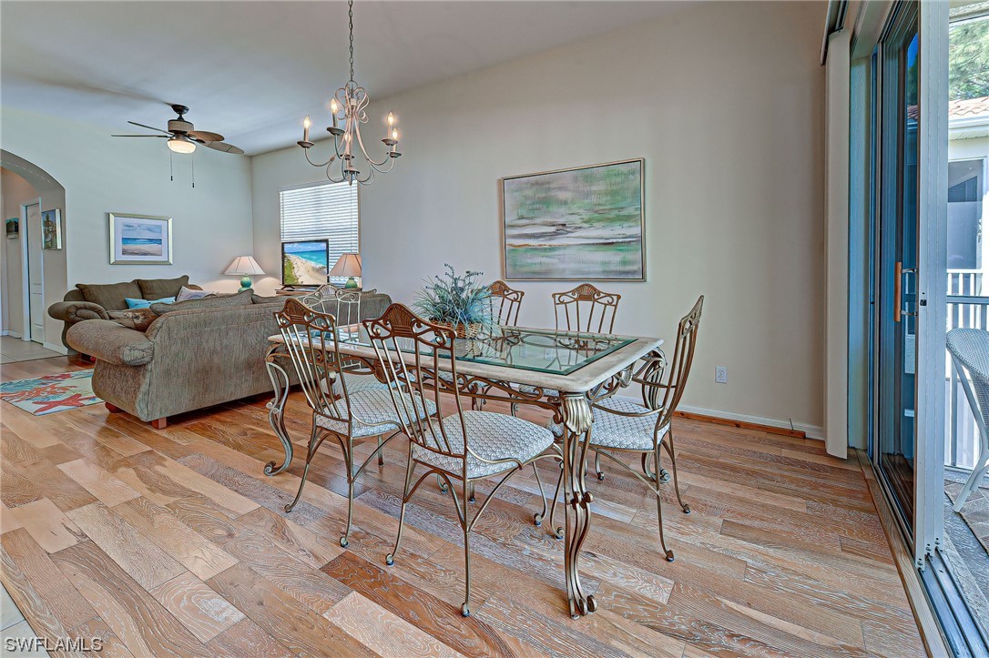 604 Ravinia Circle, Unit 604 Venice, FL 34292 - Photo 15 of 37 a dining room with wooden floor a chandelier a glass table and chairs