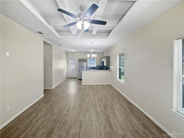 a view of a hallway with wooden floor and a kitchen