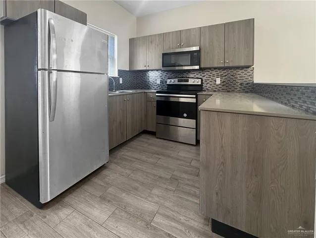 a kitchen with stainless steel appliances a refrigerator and a stove top oven
