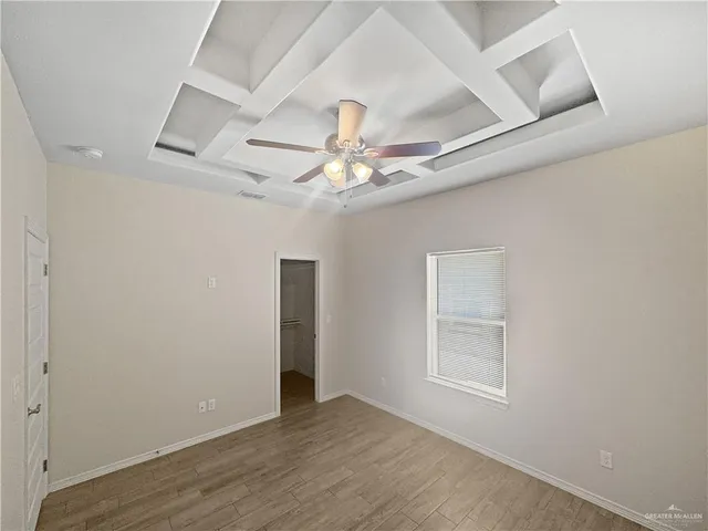 an empty room with wooden floor chandelier fan and windows