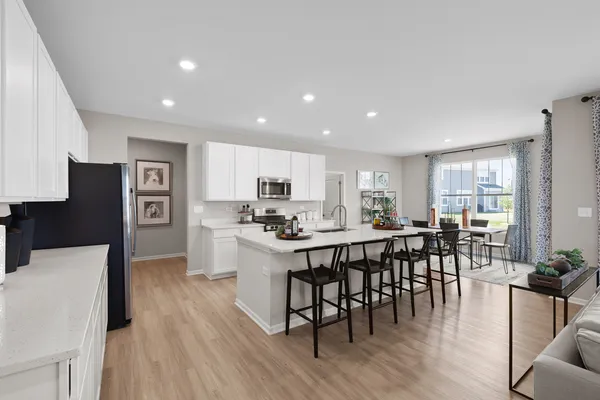 a kitchen with stainless steel appliances a dining table chairs stove refrigerator and cabinets