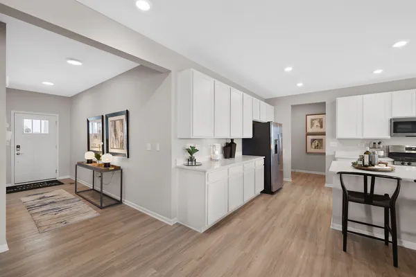 a large white kitchen with wooden floor and stainless steel appliances