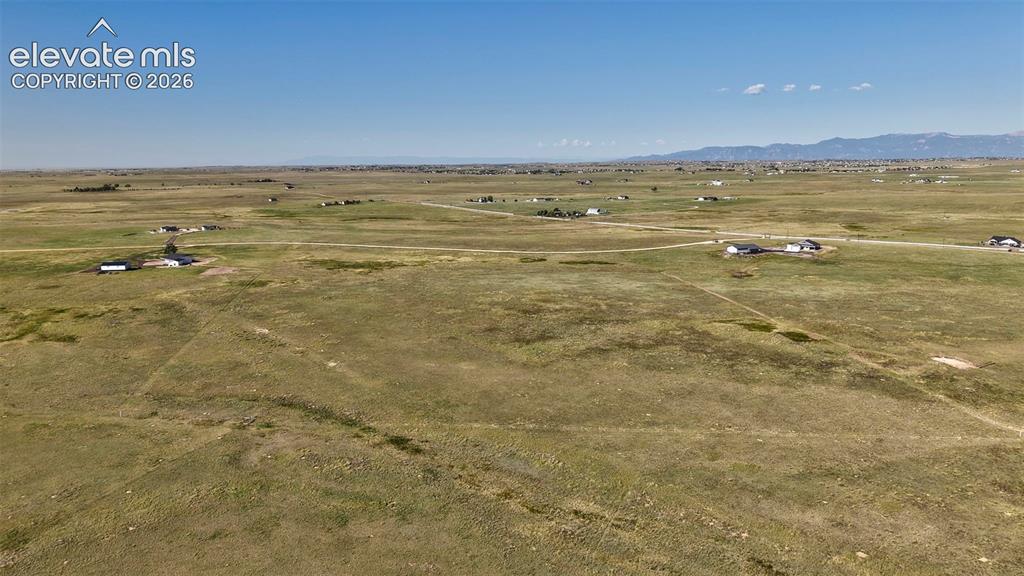 8007 Wrangler Ranch View Peyton, CO 80831 - Photo 7 of 9 Expansive rural landscape featuring scattered residential properties, a clear blue sky, and distant mountain ranges