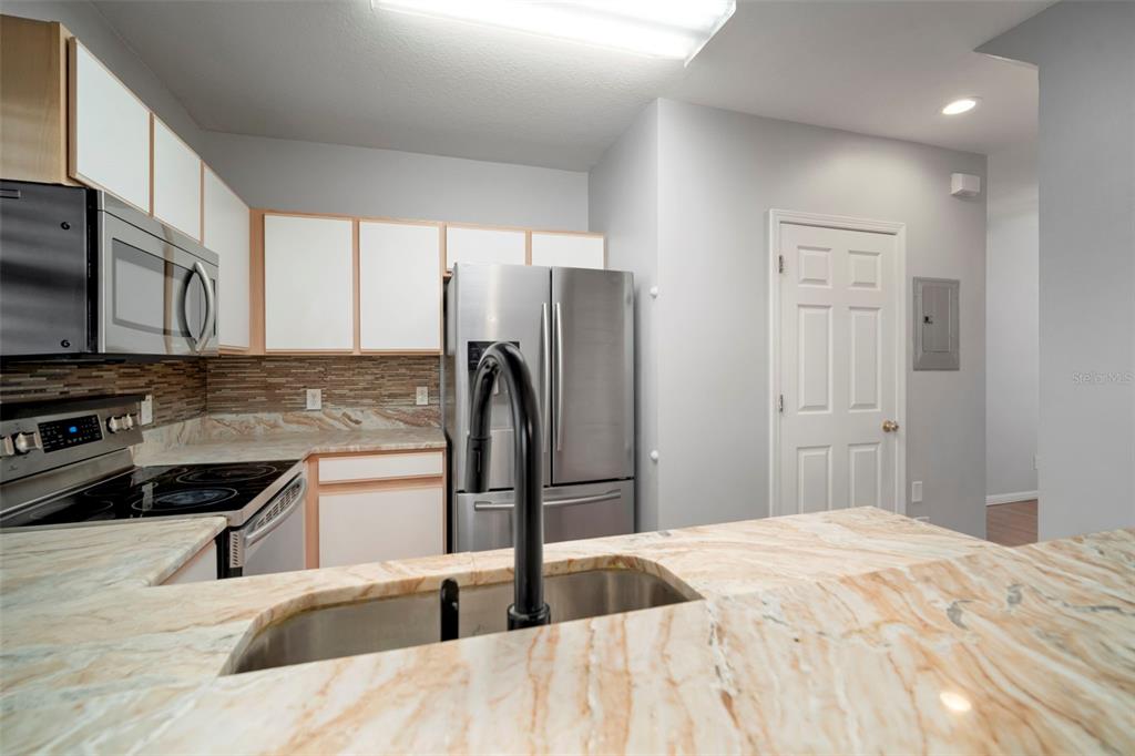 1231 Charlesworth Drive Wesley Chapel, FL 33543 - Photo 12 of 41 a kitchen with stainless steel appliances kitchen island granite countertop a refrigerator a stove a sink a microwave and island