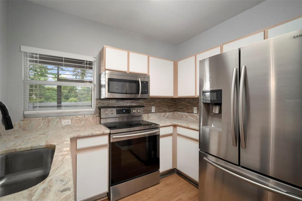 1231 Charlesworth Drive Wesley Chapel, FL 33543 - Photo 13 of 41 a kitchen with stainless steel appliances a refrigerator stove and microwave