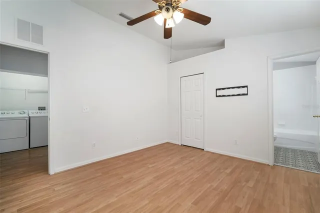 a view of empty room with wooden floor and ceiling fan