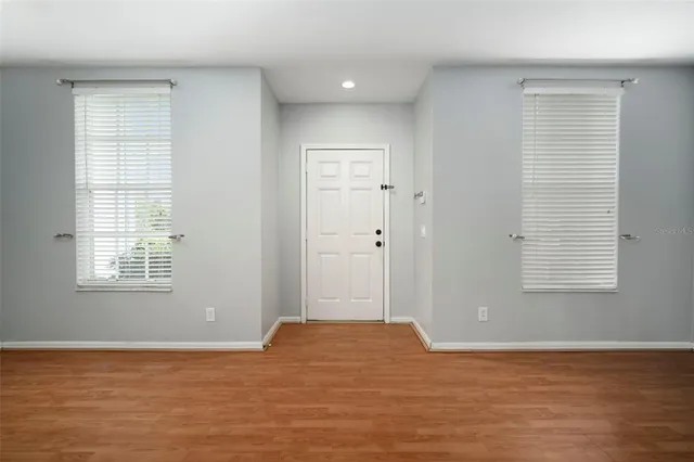 a view of an empty room with wooden floor and a kitchen