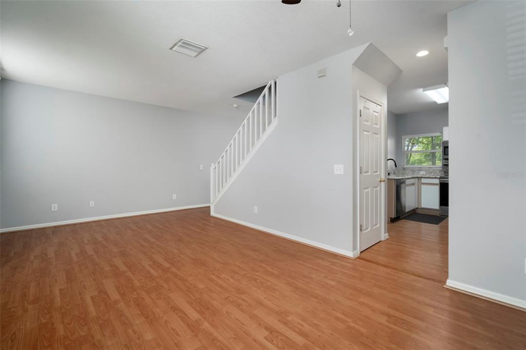 1231 Charlesworth Drive Wesley Chapel, FL 33543 - Photo 7 of 41 a view of an empty room with wooden floor and a kitchen