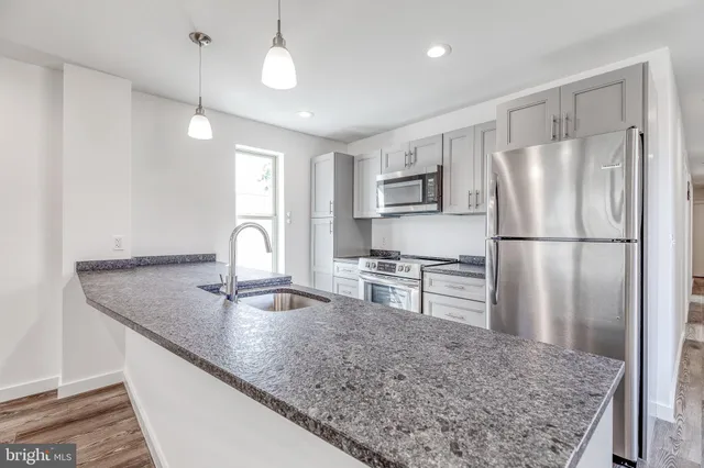 a kitchen with stainless steel appliances granite countertop a sink refrigerator and microwave