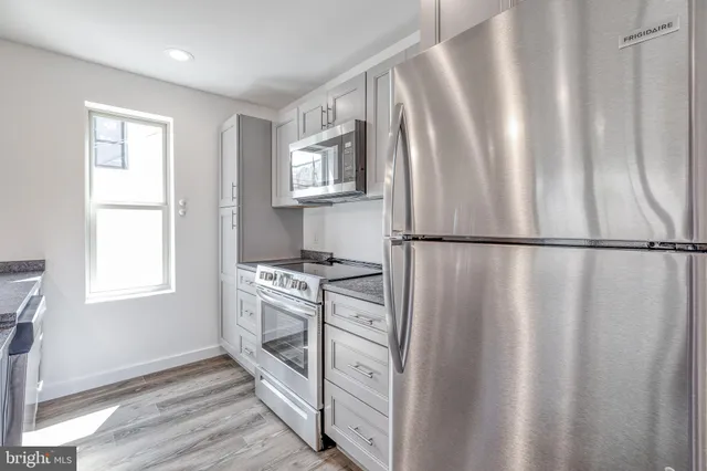 a kitchen with stainless steel appliances granite countertop a refrigerator a sink and a stove top oven