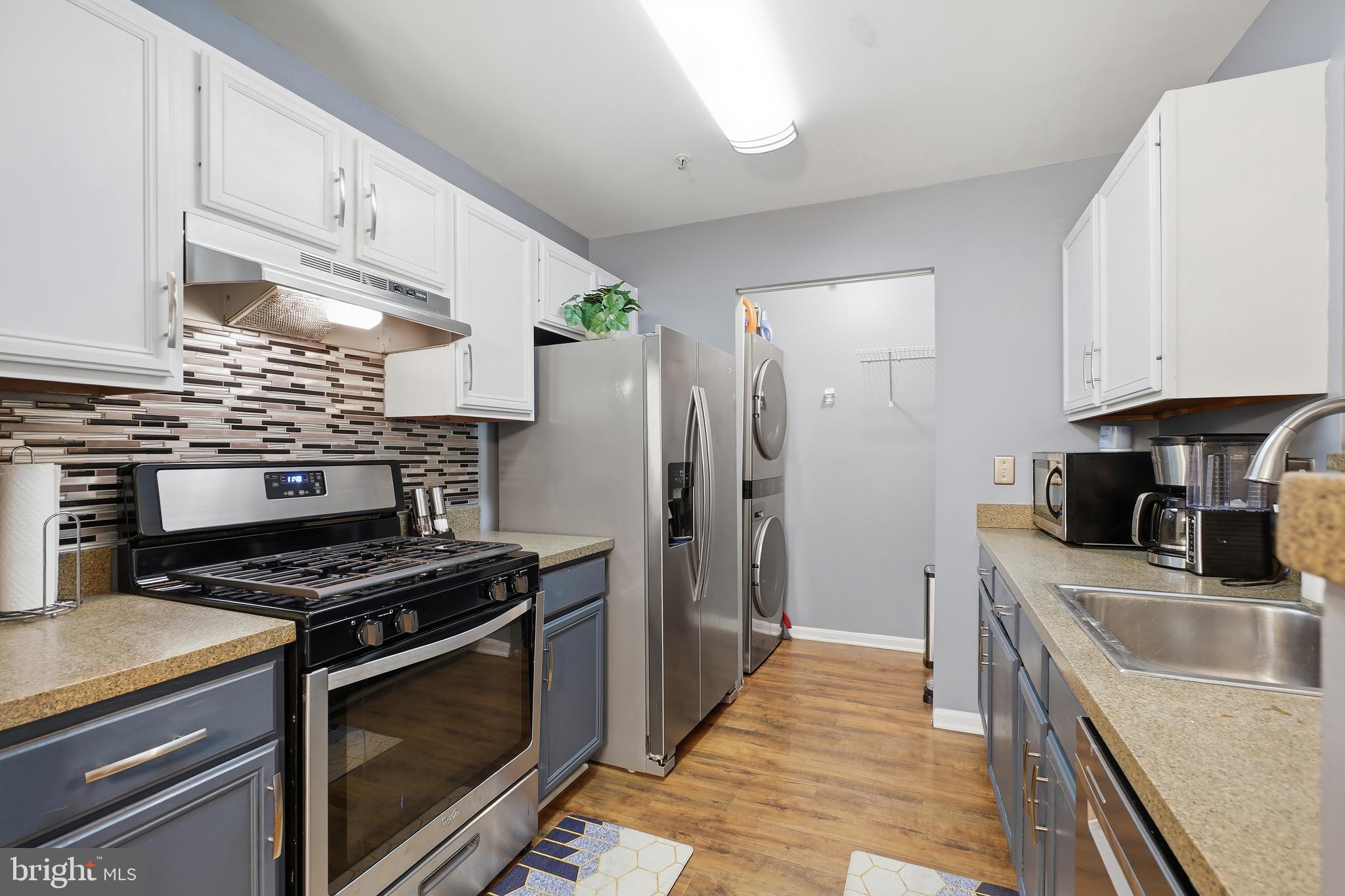 14151 Cuddy Loop, Unit 101 Woodbridge, VA 22193 - Photo 21 of 45 a kitchen with stainless steel appliances a stove a sink a refrigerator white cabinets and wooden cabinets